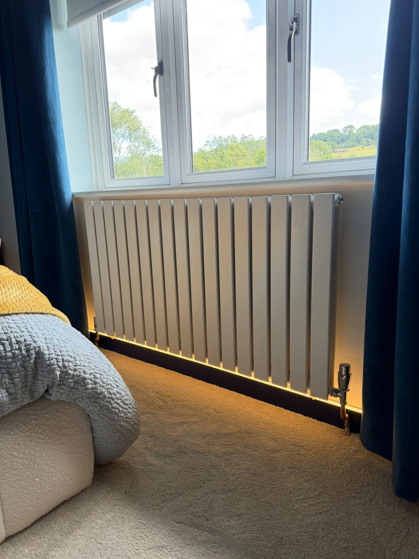 New white vertical flat-panel designer radiator installed under bedroom window in Coventry