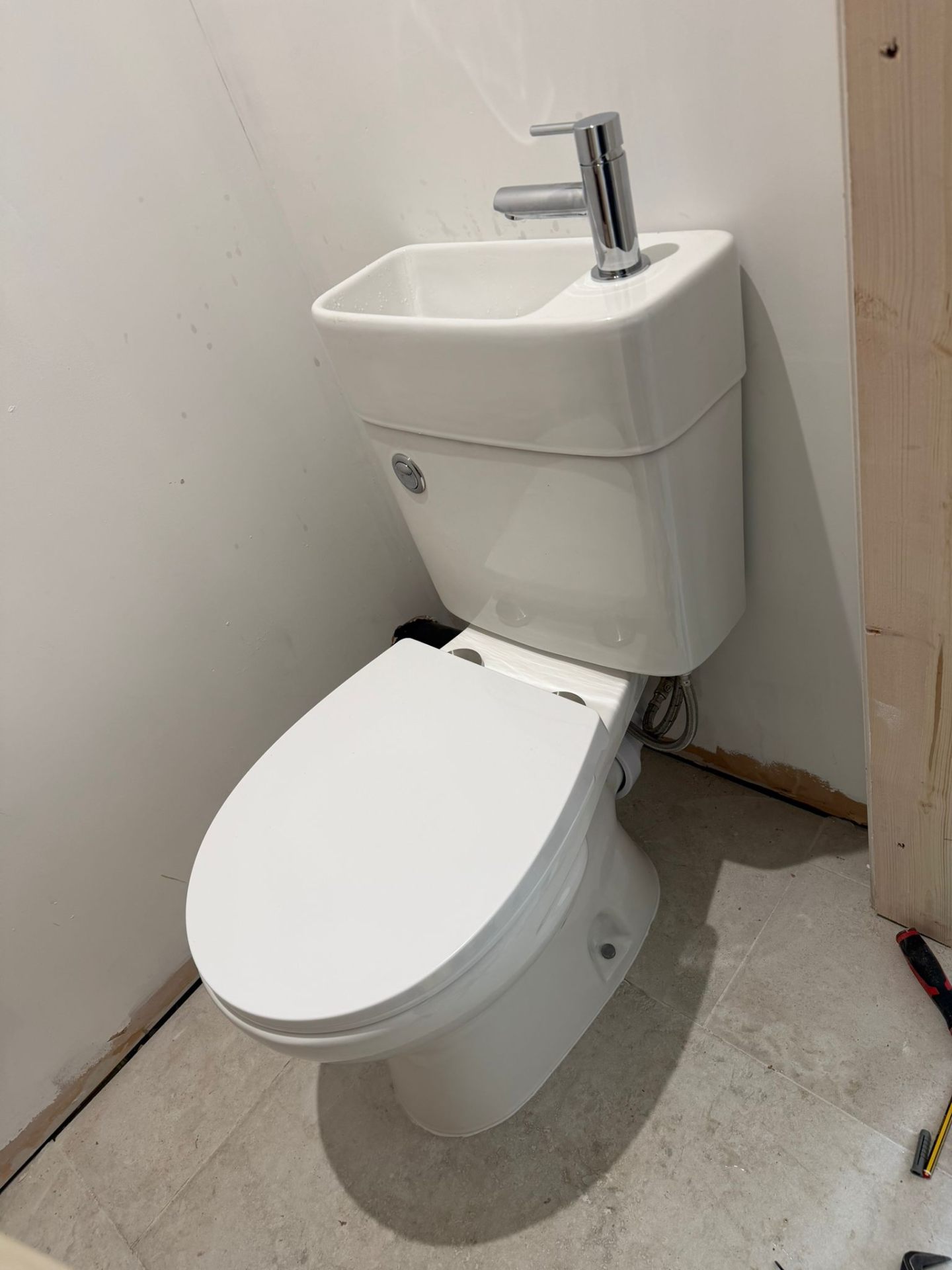 Space-saving close-coupled toilet with integrated cloakroom basin and chrome tap installed in WC