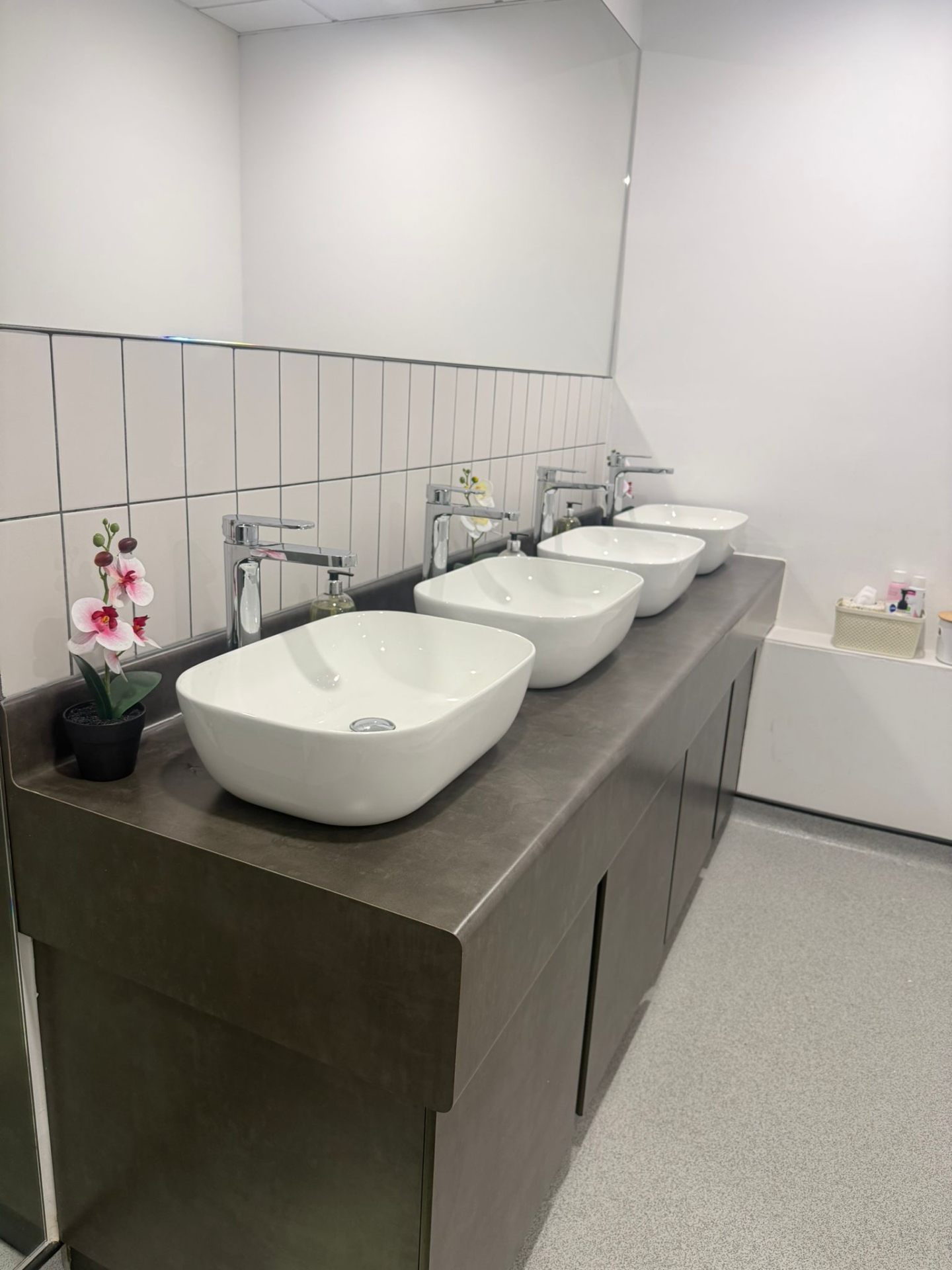 Commercial washroom refurbishment with row of countertop basins and chrome taps
