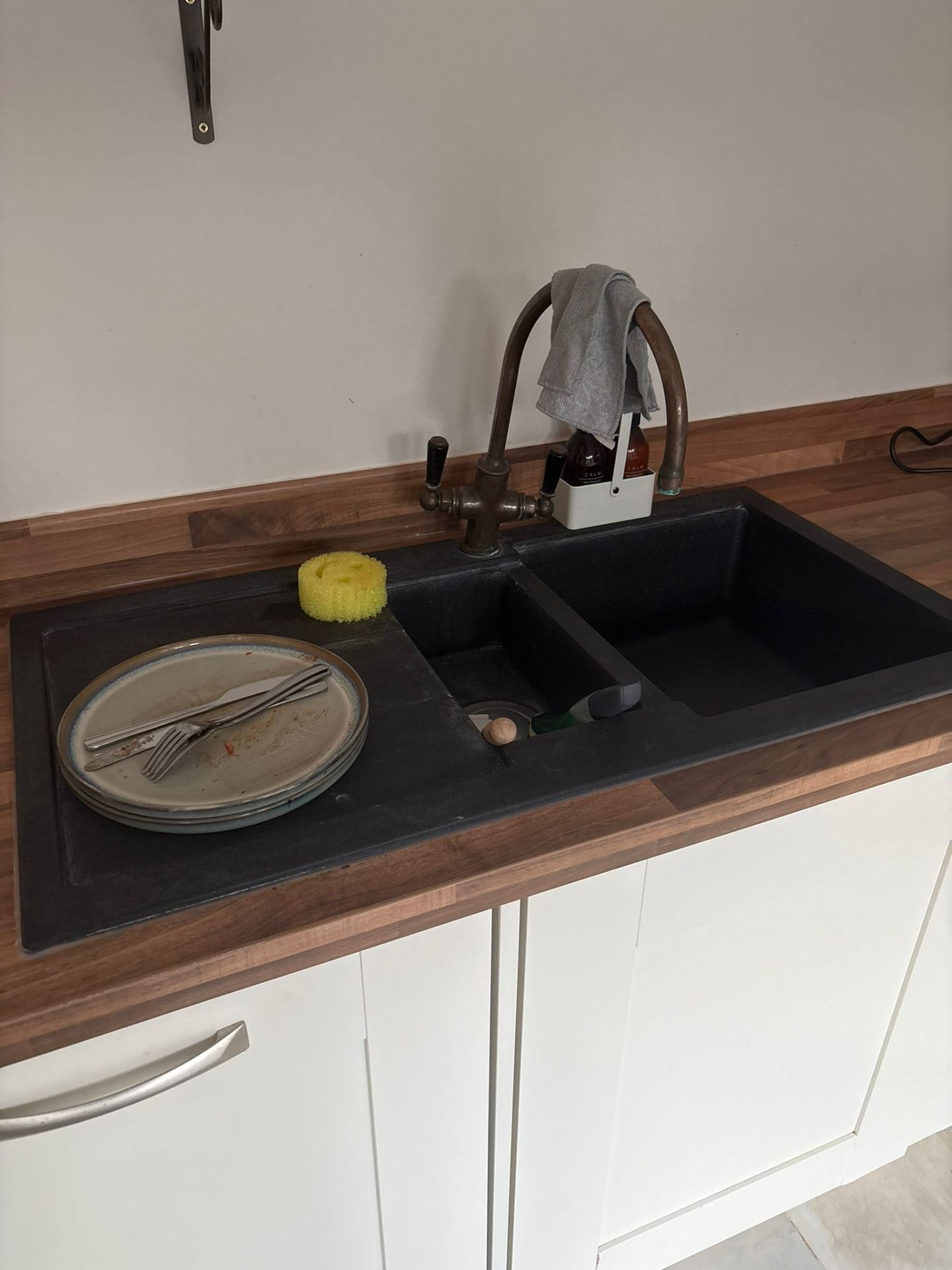 Black granite composite 1.5 bowl sink with traditional brass bridge mixer tap on walnut worktop