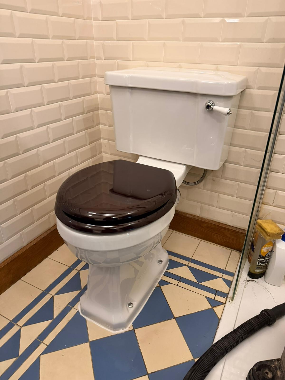Traditional close-coupled toilet with dark wood seat fitted in metro-tiled bathroom, Coventry